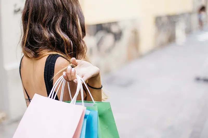 Woman walking down street carrying multiple shopping bags