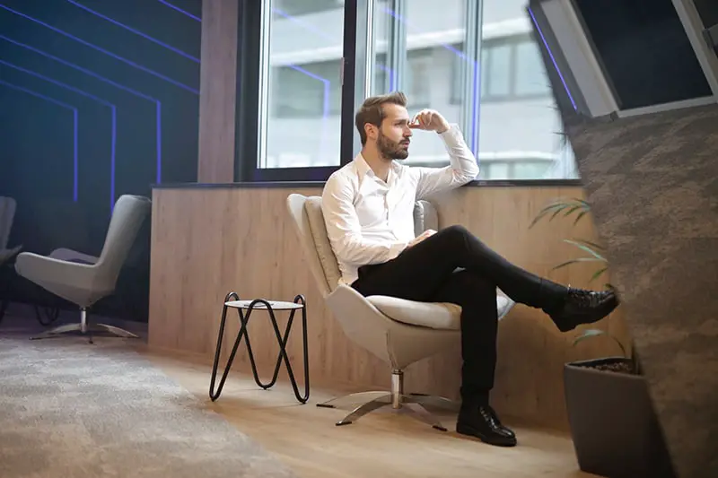 Man sitting in chair near window and looking out following unfair dismissal
