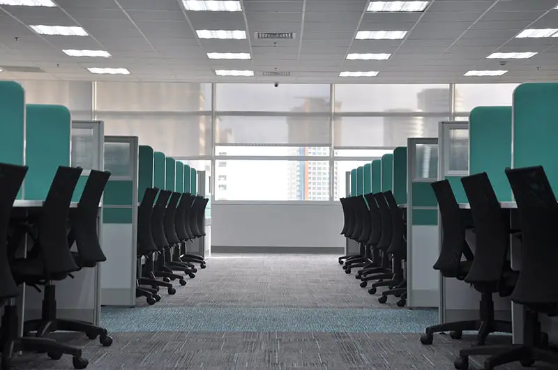 empty black rolling chairs at office workstation cubicles