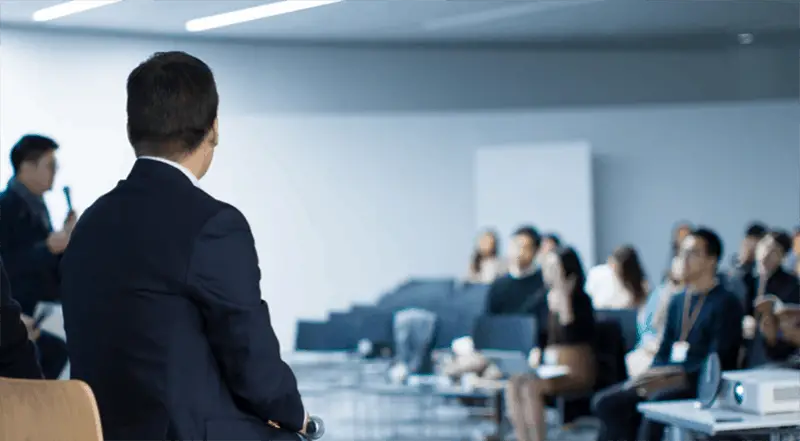 People sitting in a corporate conference room listening to speaker