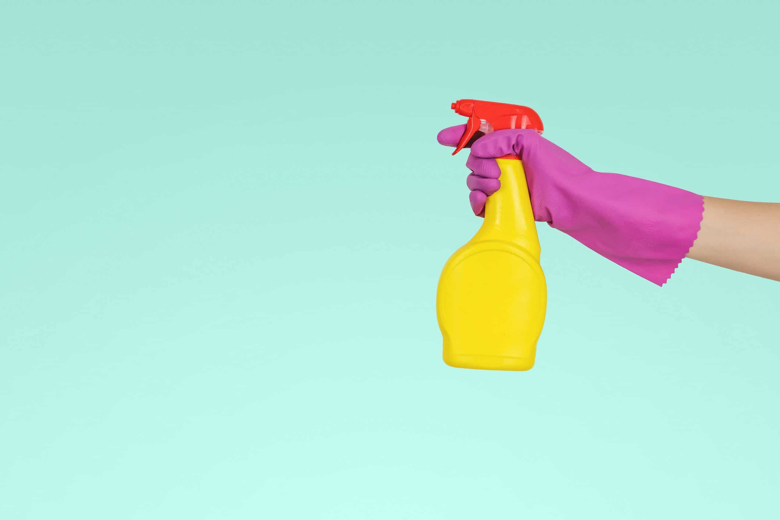 person holding yellow plastic spray bottle of cleaning products