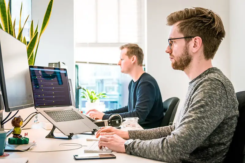 staffing agency staff sitting on chair wearing gray crew-neck long-sleeved shirt using Apple Magic Keyboard