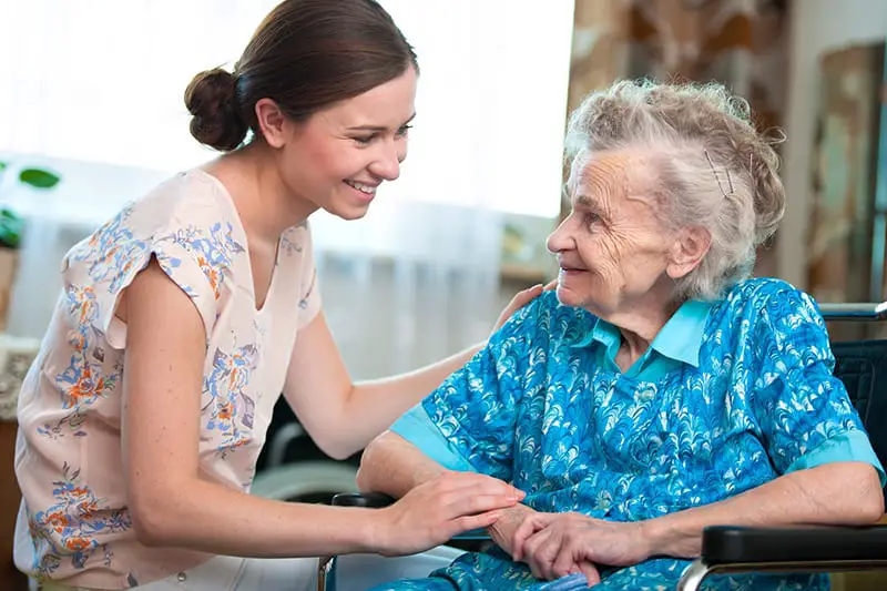 A healhcare woman and an old woman in a wheelchair