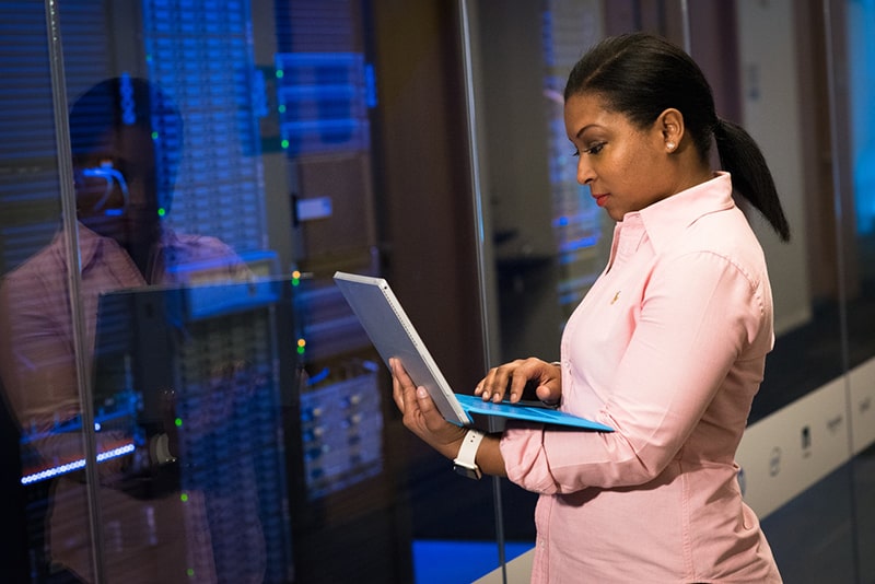 Woman holding a laptop outside computer server room