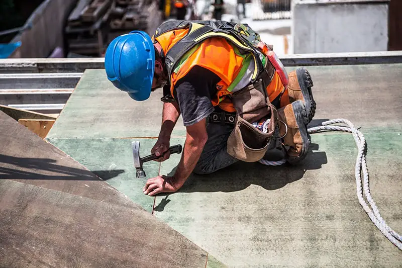 construction worker wearing a blue hard hat using hammer on construction site