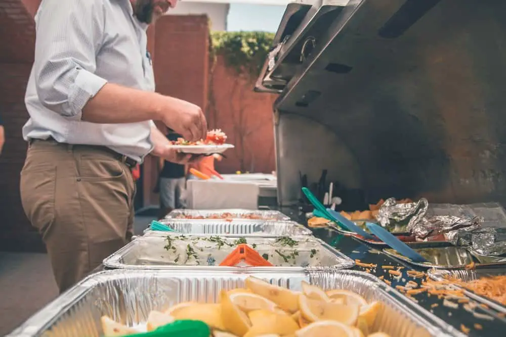 man picking food from foil on trays