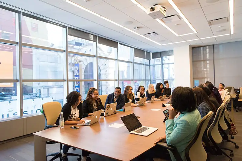 employees sitting around boardroom table in air-conditioned office
