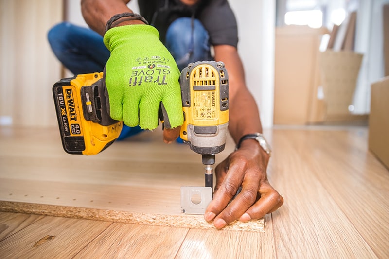 person doing home improvement with dewalt cordless impact driver on brown board