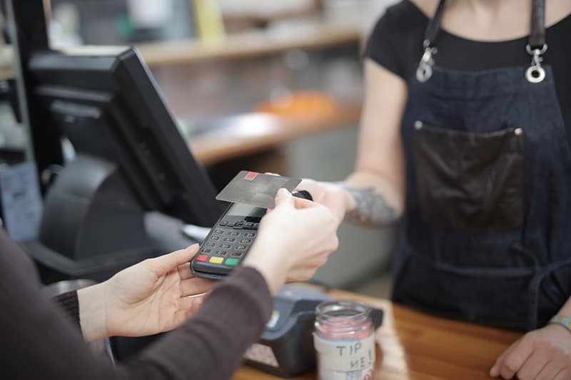 person holding credit card above credit card processing machine
