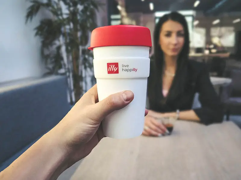 person holding red and white live happily cup