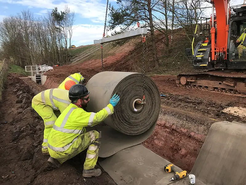 Workmen on site using concrete canvas fabric - Geosynthetic Cementitious Composite Mats -  GCCMs