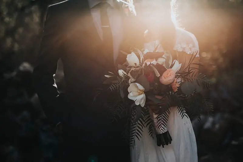 Wedding photo of groom standing next to bride holding bouquet of flowers