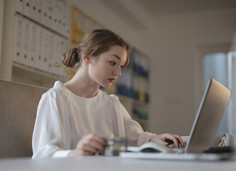 woman in white long sleeved shirt using laptop