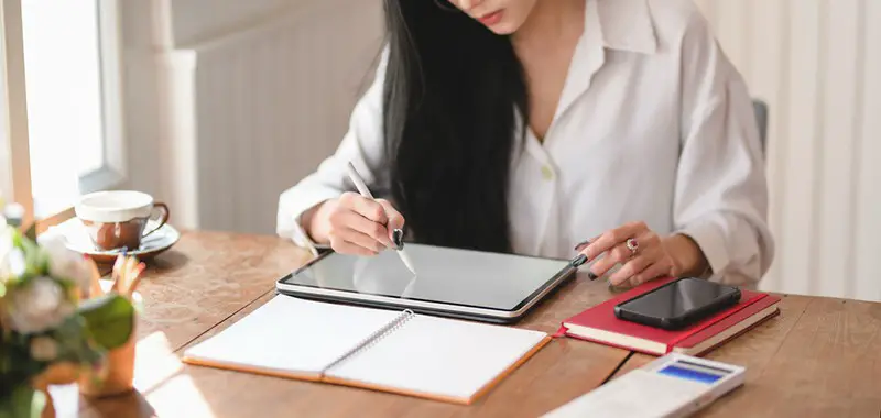 Person working from home writing on a tablet