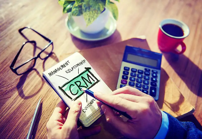 A man pointing the pen to a small notepad while analyzing CRM illustration