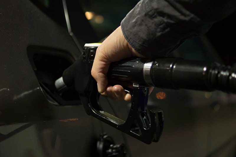 A man in a black sleeve putting fuel in vehicle