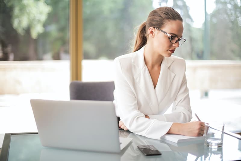 female remote worker witting a desk and writing on a note pad