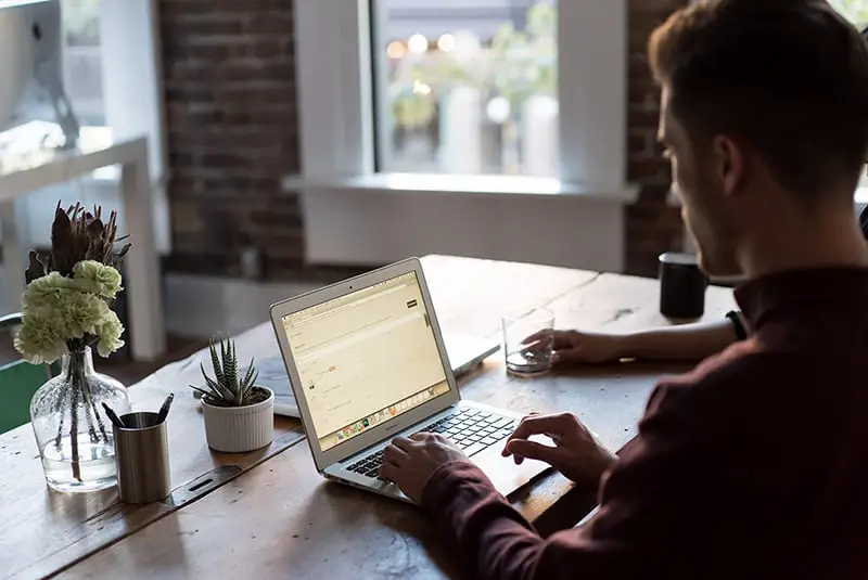 Person working on a laptop at a table, sitting next to someone