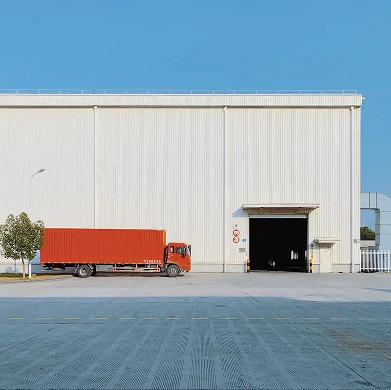 Red delivery truck – freight truck parked beside a warehouse building