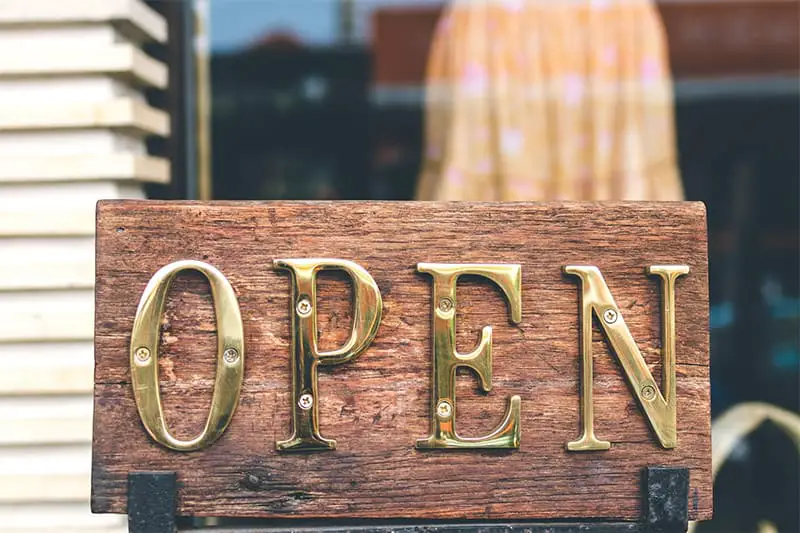 An OPEN signage in gold text in glass door