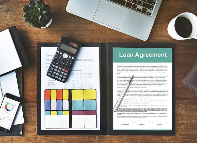 Loan agreement form with pen and calculator on the top of wooden table