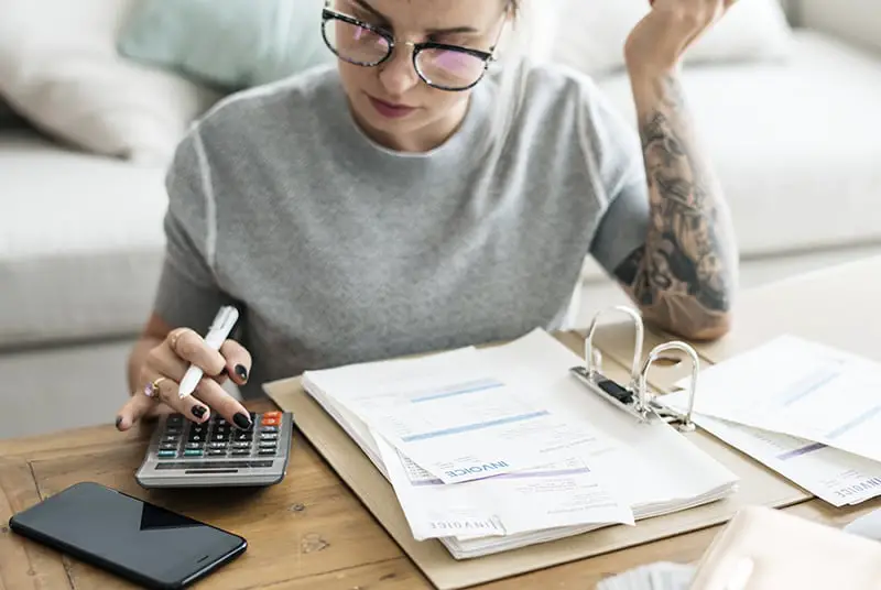 Tattooed girl doing calculations on her bills