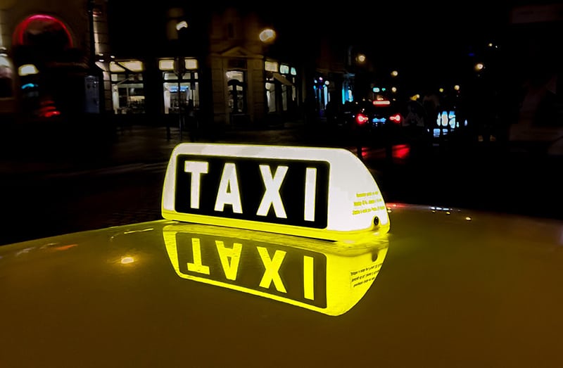 lit taxi signage reflected on the roof of a taxi cab