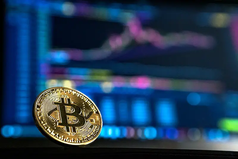 Bitcoin – cryptocurrency set against blurred image of forex trading charts
