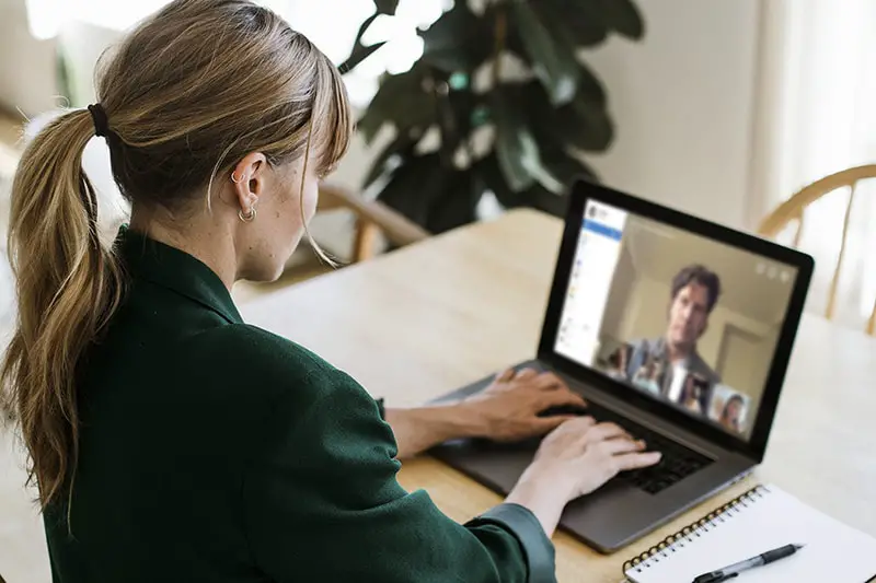 Woman wearing green blazer chatting to a person on video conference