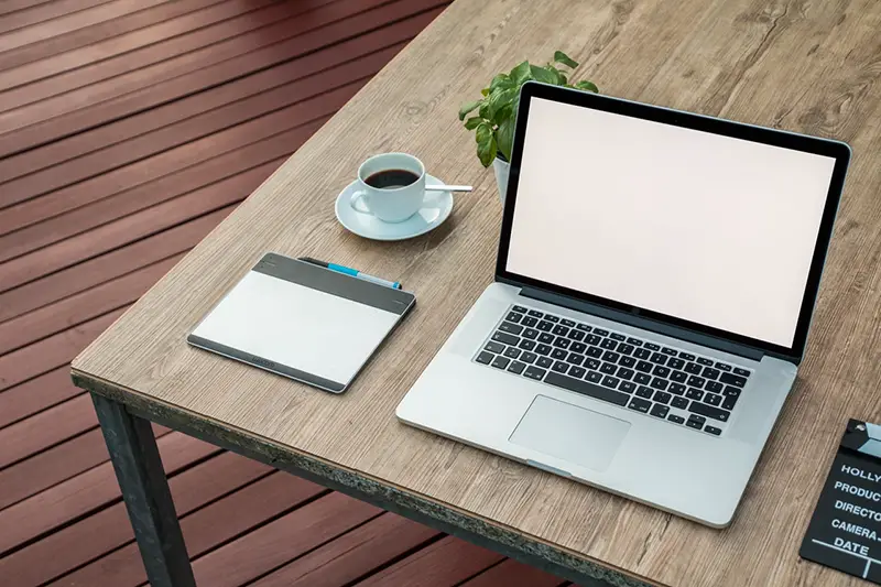 Laptop on a table next to  a cup of coffee 