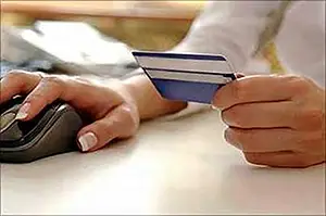 A hand of a woman holding computer mouse and a credit card