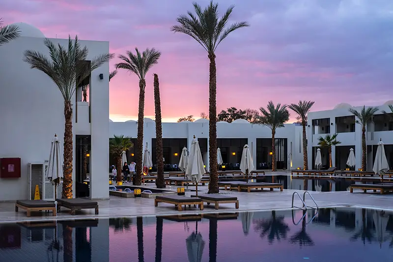 Poolside in hotel resort complex – palm trees and sunbeds