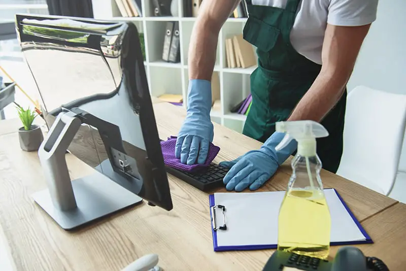 A man wearing gloves while cleaning the keyboard