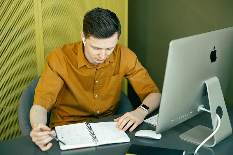Man working at desk looking at note book