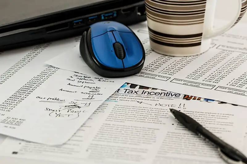 A blue wireless mouse, stripe cup, black pen, and tax incentives computation