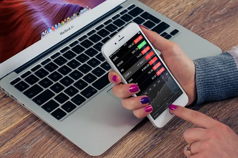 A woman holding smartphone with the screen showing analytical reports