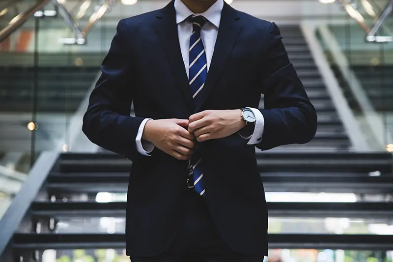 A business man wearing suit and tie fixing his coat button
