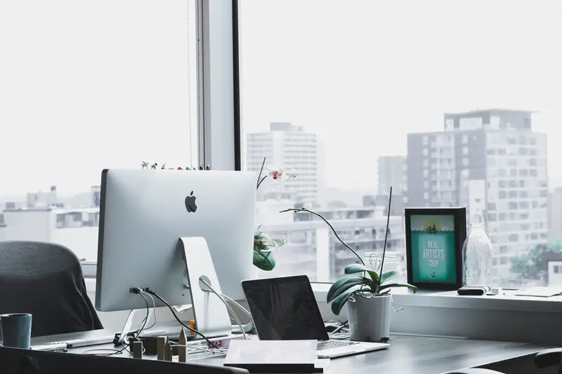 Computer on desk next to a window in an office