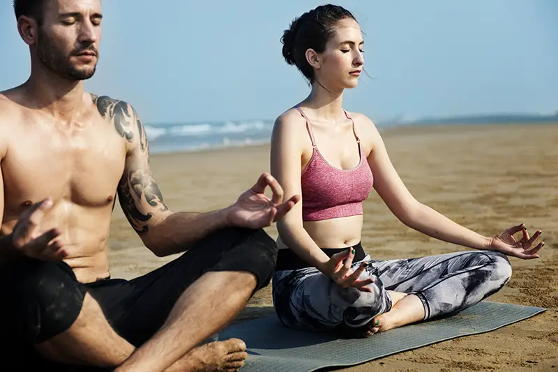 A couple doing meditation on the sea shore