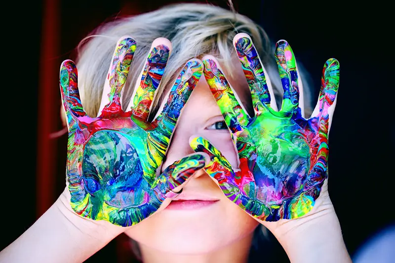 blur image of boy with paint on hands in a child care setting
