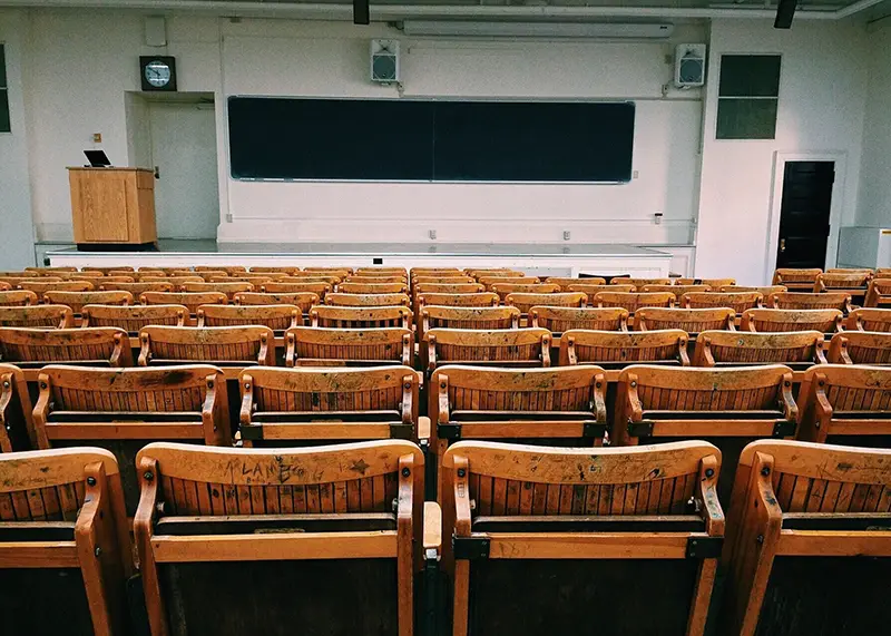 An empty classroom with black board and wooden arm chairs