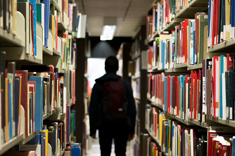 A man with backpack standing in the   library