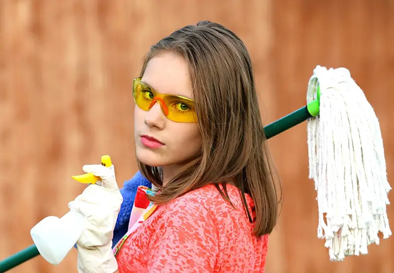 Woman holding mop and cleaning products to clean workplace