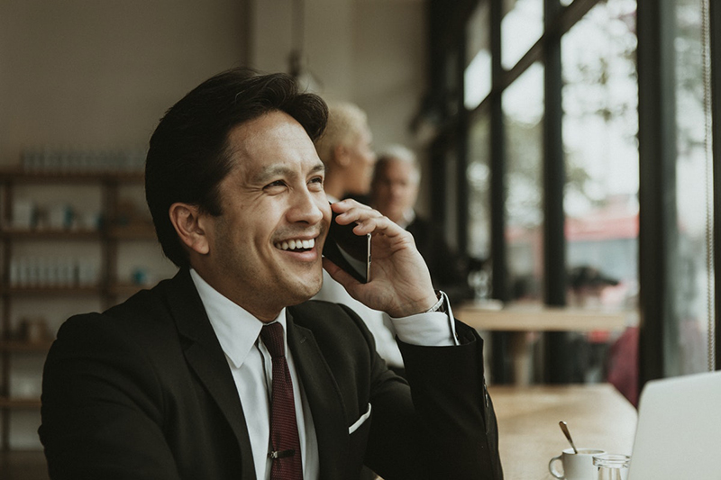 happy businessman speaking on phone in café