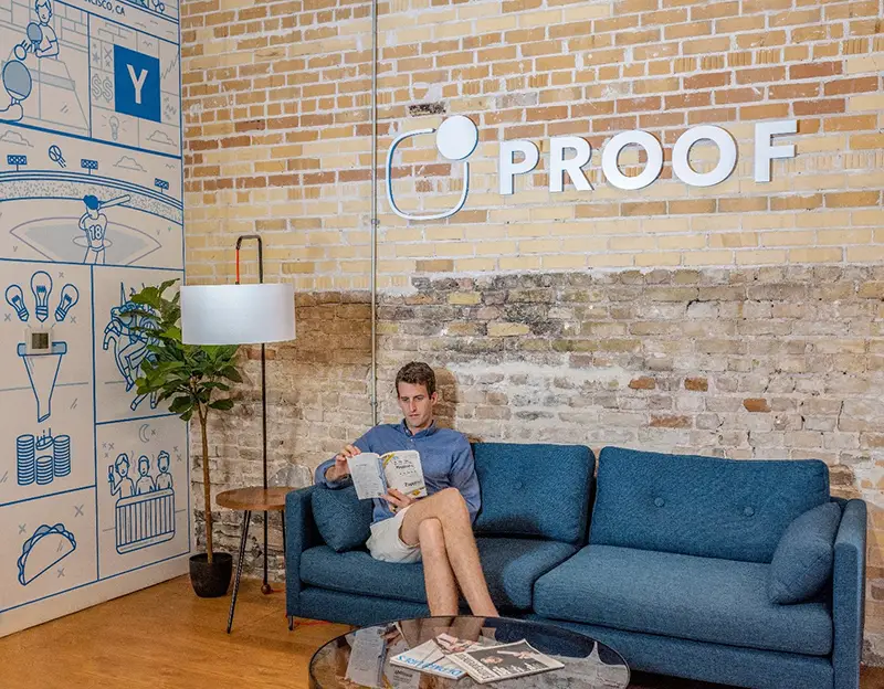 Business owner sitting on a blue sofa in an office, reading a book