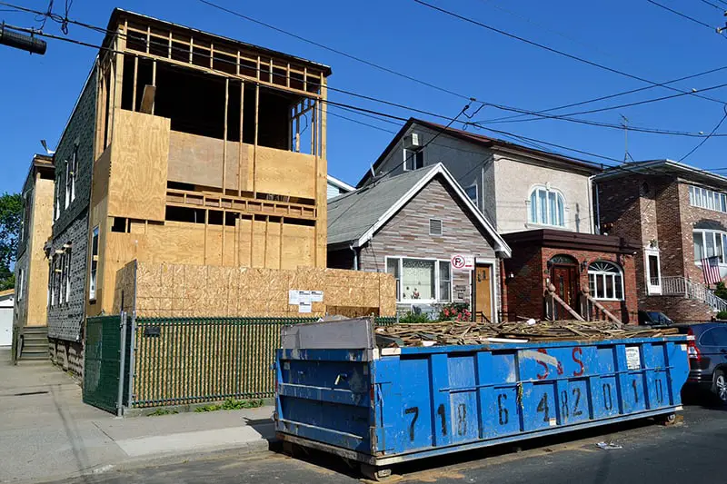 Roll away dumpster on street in front of a house under construction