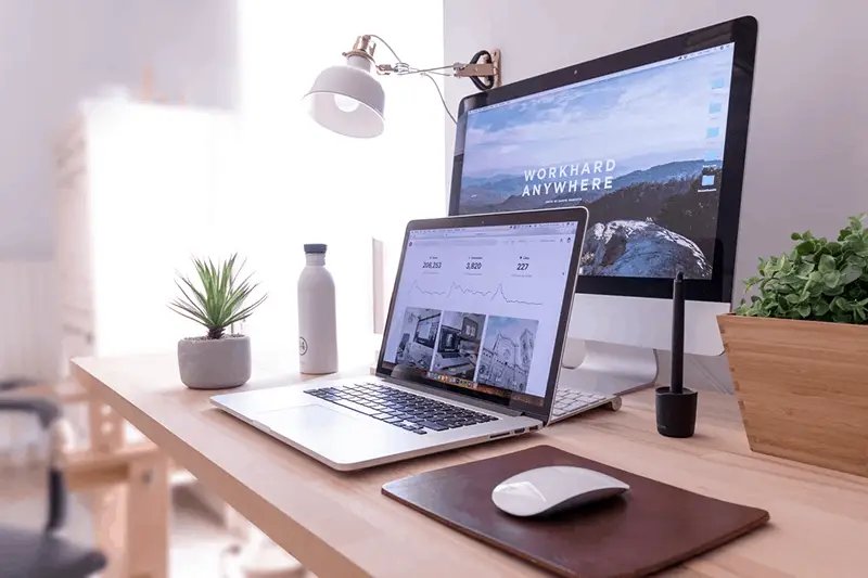 An organized working desk with laptop and monitor