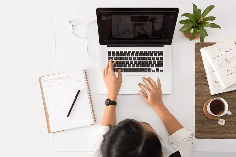 A woman on white tops in front of  her laptop