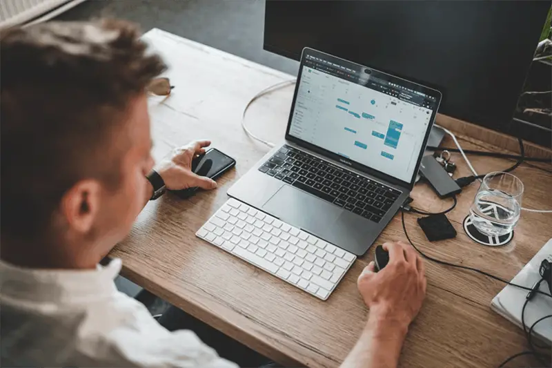 A man in front of laptop while scrolling with the mouse