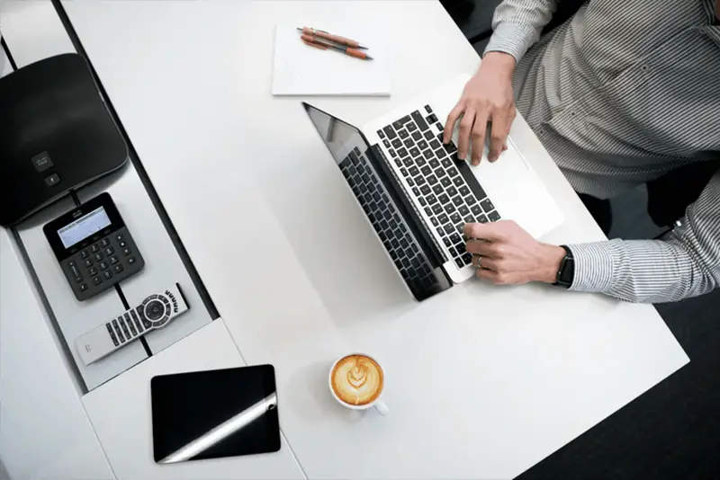 A man wearing stripes long sleeve polo working in his laptop